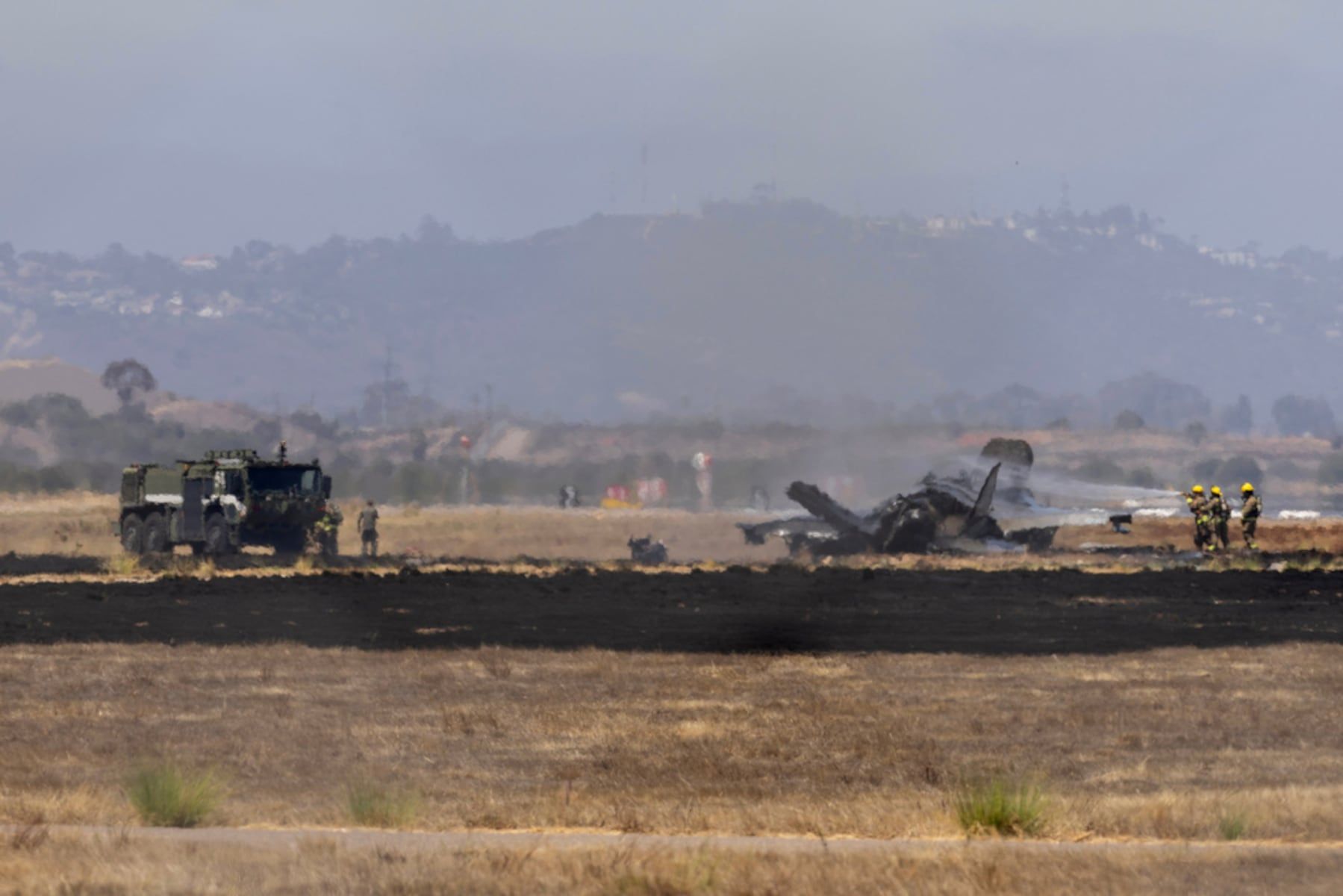 Crews work to douse an F-35 fighter jet that crashed near the runway at Marine Corps Air Station Miramar on July 31, 2026, in San Diego. - Luke Johnson/The San Diego Union-Tribune via AP