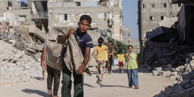 A Palestinian boy carrying a bag walks through a heavily damaged street in Khan Yunis in the southern Gaza Strip on July 31, 2026. - lemonde.fr