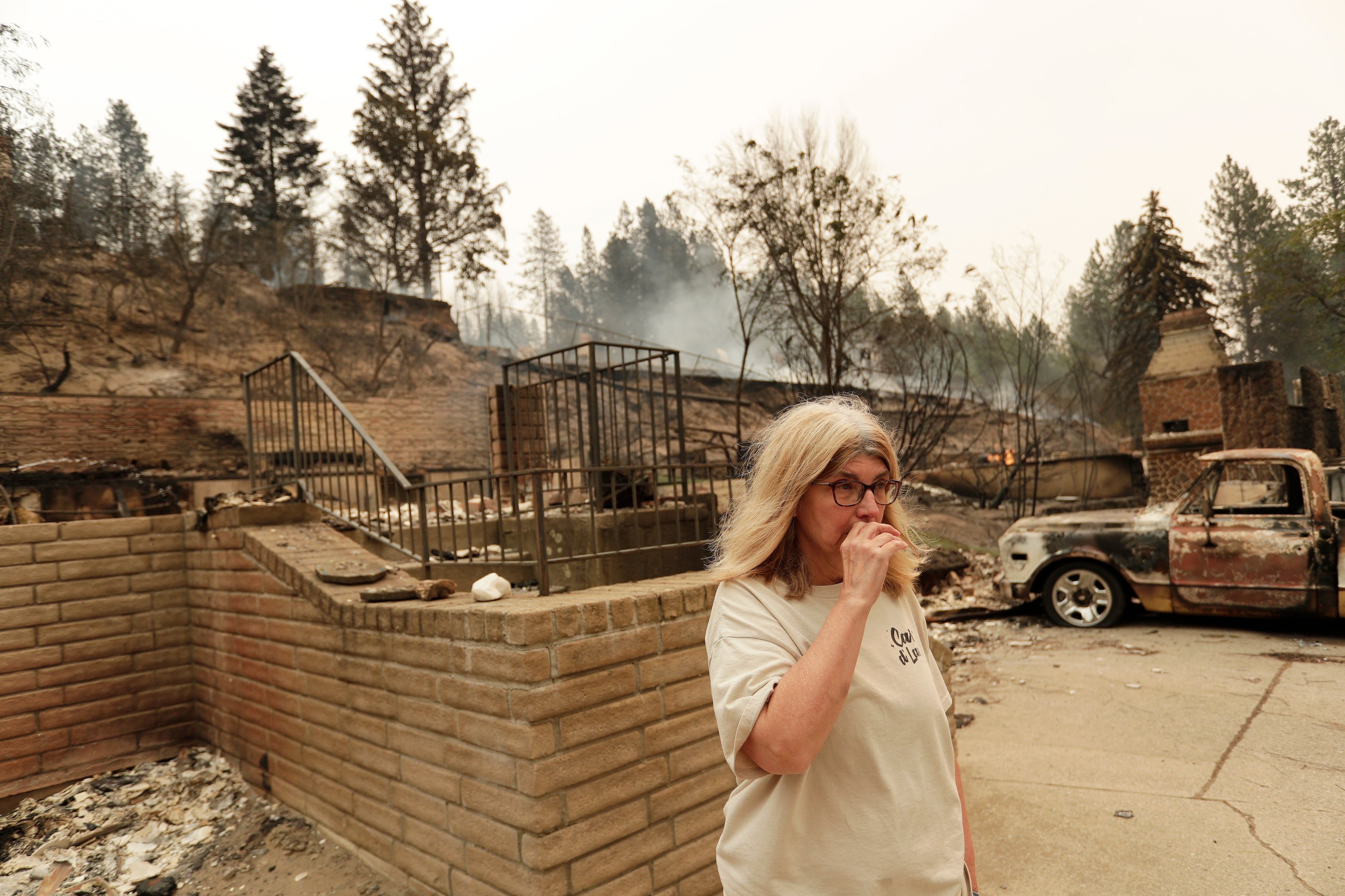Kimberley Sather stands at the duplex she rents on W. Indian Trail Road after it burned in a wildfire in Spokane, Washington, on Aug. 2, 2026. - AP Photo/Young Kwak