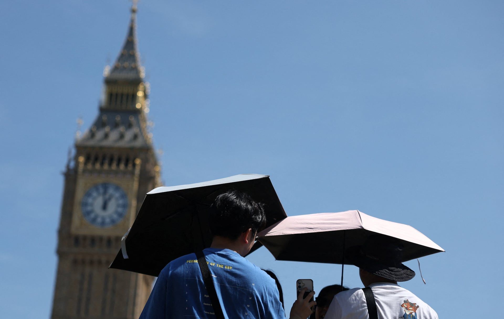 People shield themselves from the sun using umbrellas near the Elizabeth Tower and the Houses of Parliament as heat-health alert and drought conditions continue in London, Britain, August 3, 2026. - REUTERS/Toby Melville