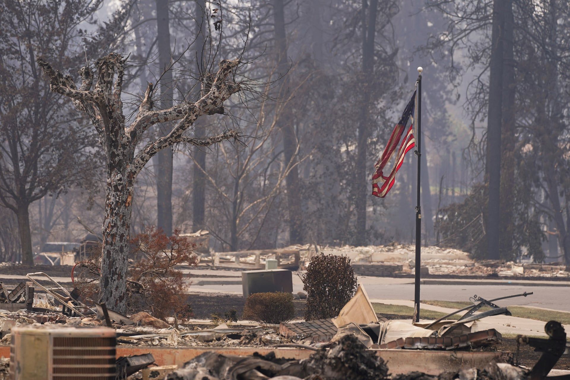 A torn American flag flutters among incinerated neighborhood in the Old Trails Fire, in Spokane, Washington, U.S., August 3, 2026. - REUTERS/David Ryder