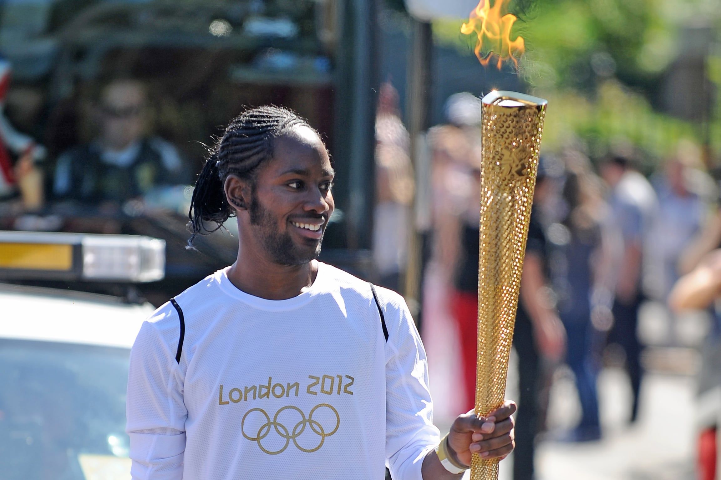 Torchbearer Jason Arday carries the Olympic Flame on the Torch Relay leg between Sutton and Merton, in London, July 23, 2012. - Joe Giddens/LOCOG/PA via AP