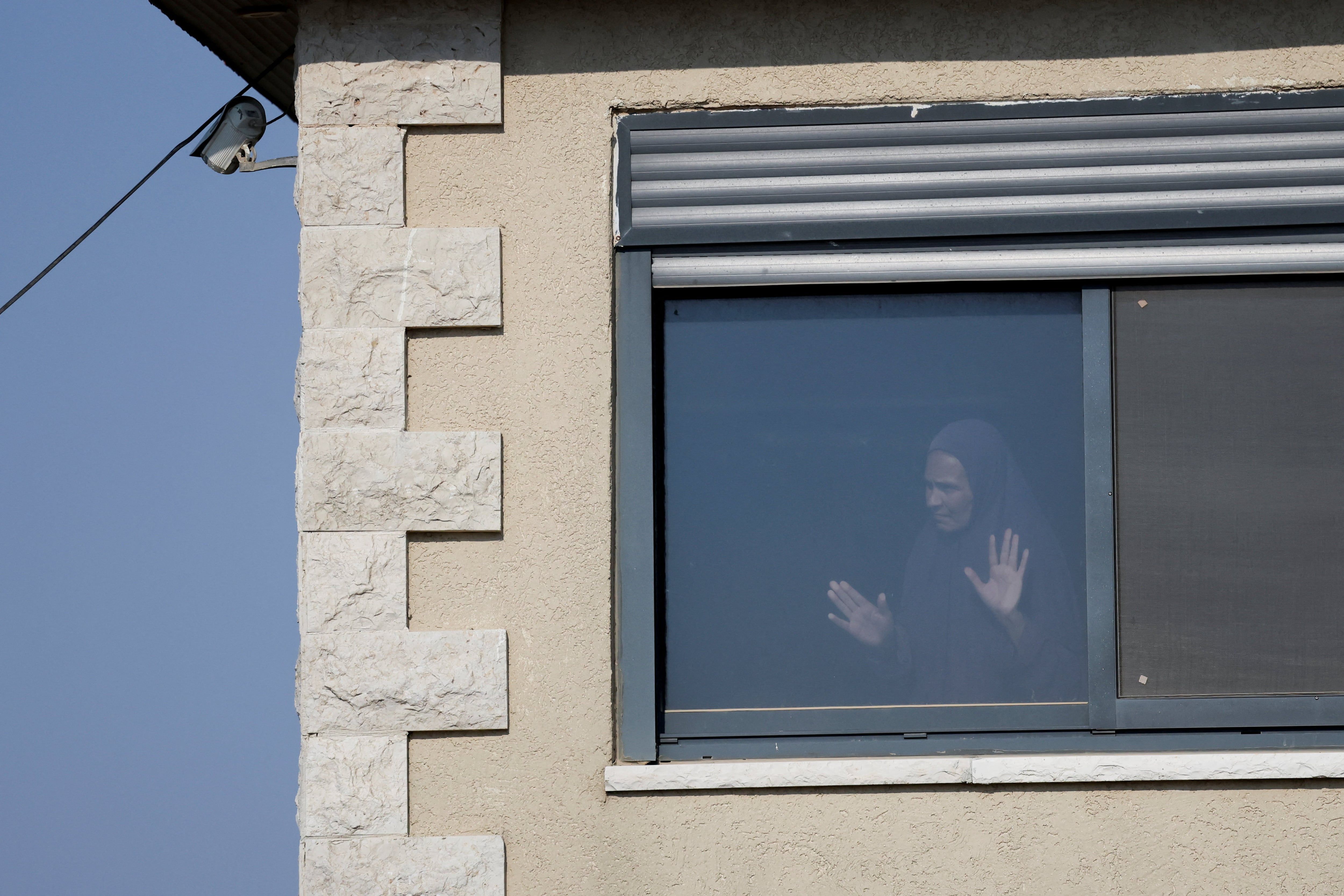 A Palestinian woman looks from a window in Qusra village. - Reuters