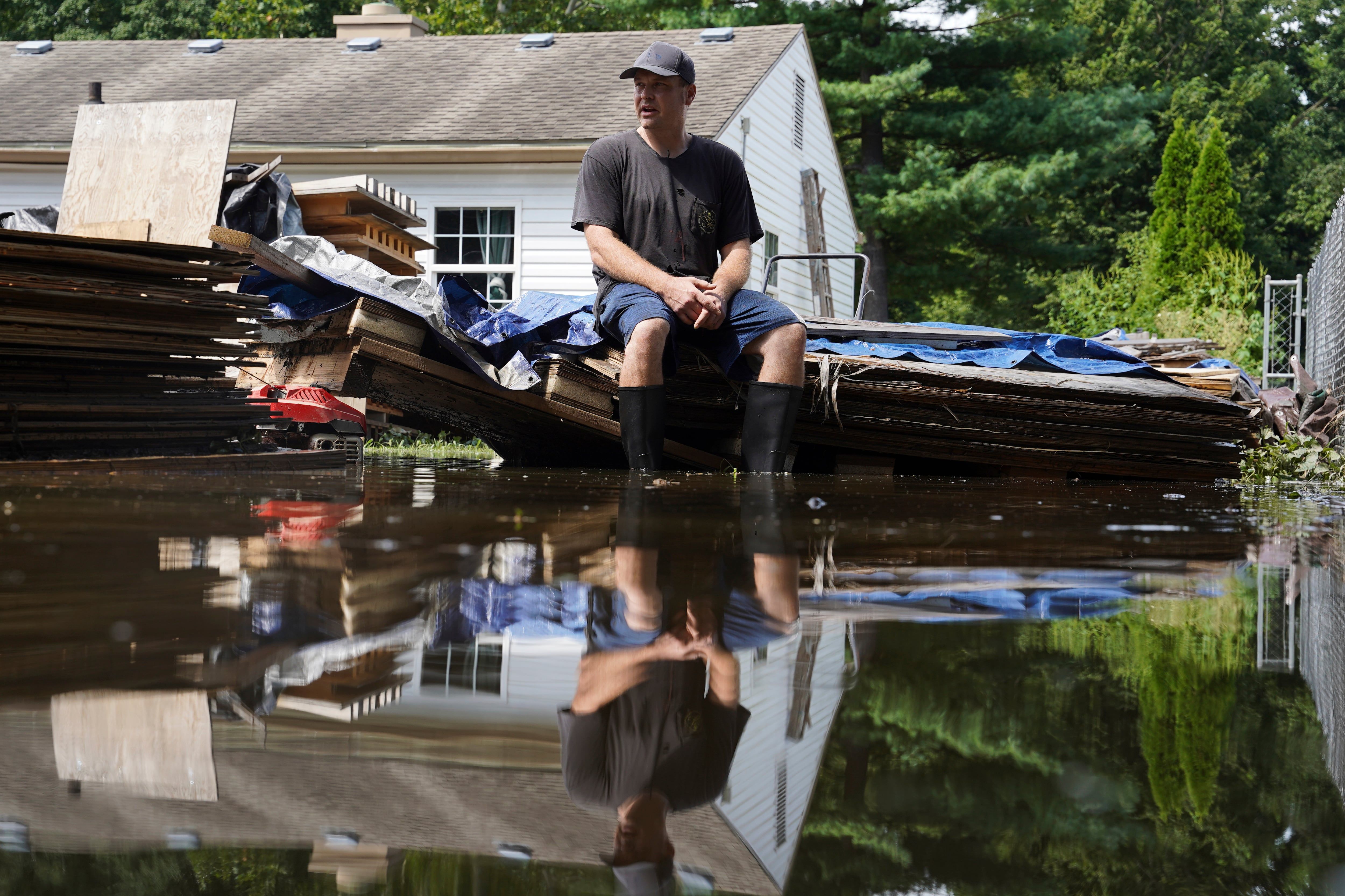 Frank Gounder sits in his flooded backyard, where his wood shop was also damaged by floodwaters, in Indianapolis, Sunday, Aug. 16, 2026. - AP Photo/Obed Lamy