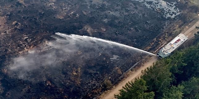 A drone view shows Belgian army firefighters spraying burned fields and forests during a wildfire burning near Waimes, High Fens region, Belgium, August 16, 2026. - lemonde.fr