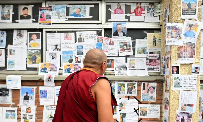 A Buddhist monk looks at photographs of missing and deceased people pasted on a wall outside Tribhuvan University Teaching Hospital in Kathmandu, Nepal. - Reuters