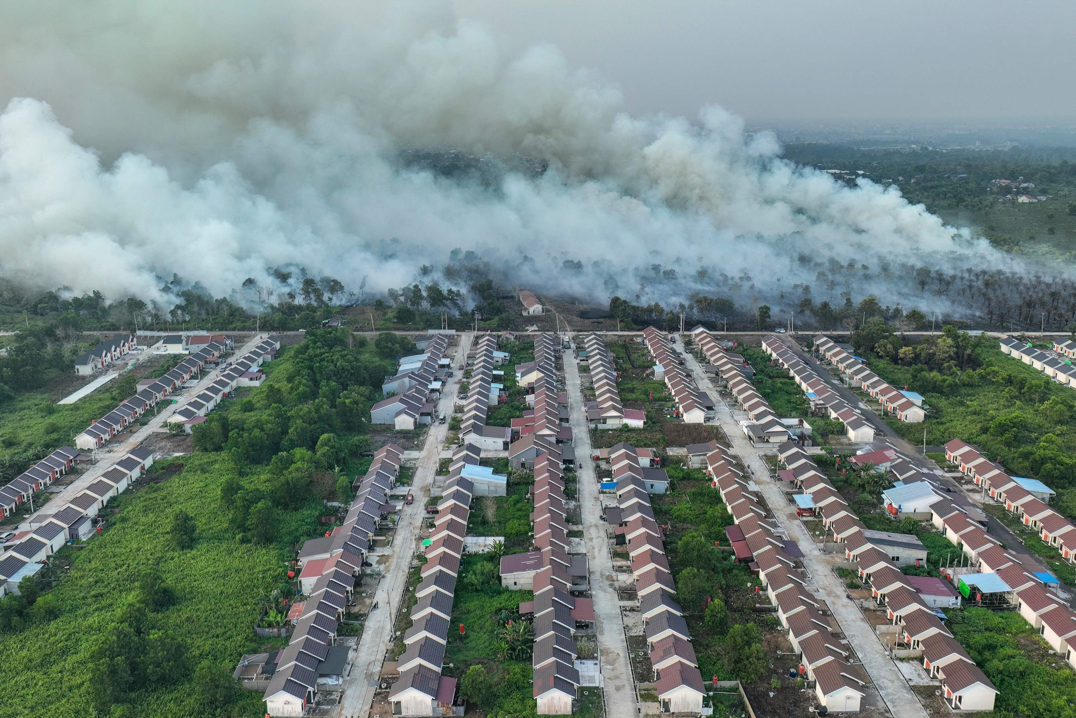 Smoke rises from a wildfire next to a housing complex in Indonesia. - AFP
