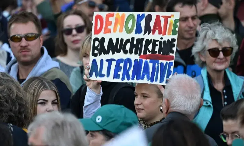Protesters hold a sign reading “Democracy does not need an alternative” during an anti-AfD demonstration in Berlin on September 12, 2026. - AFP