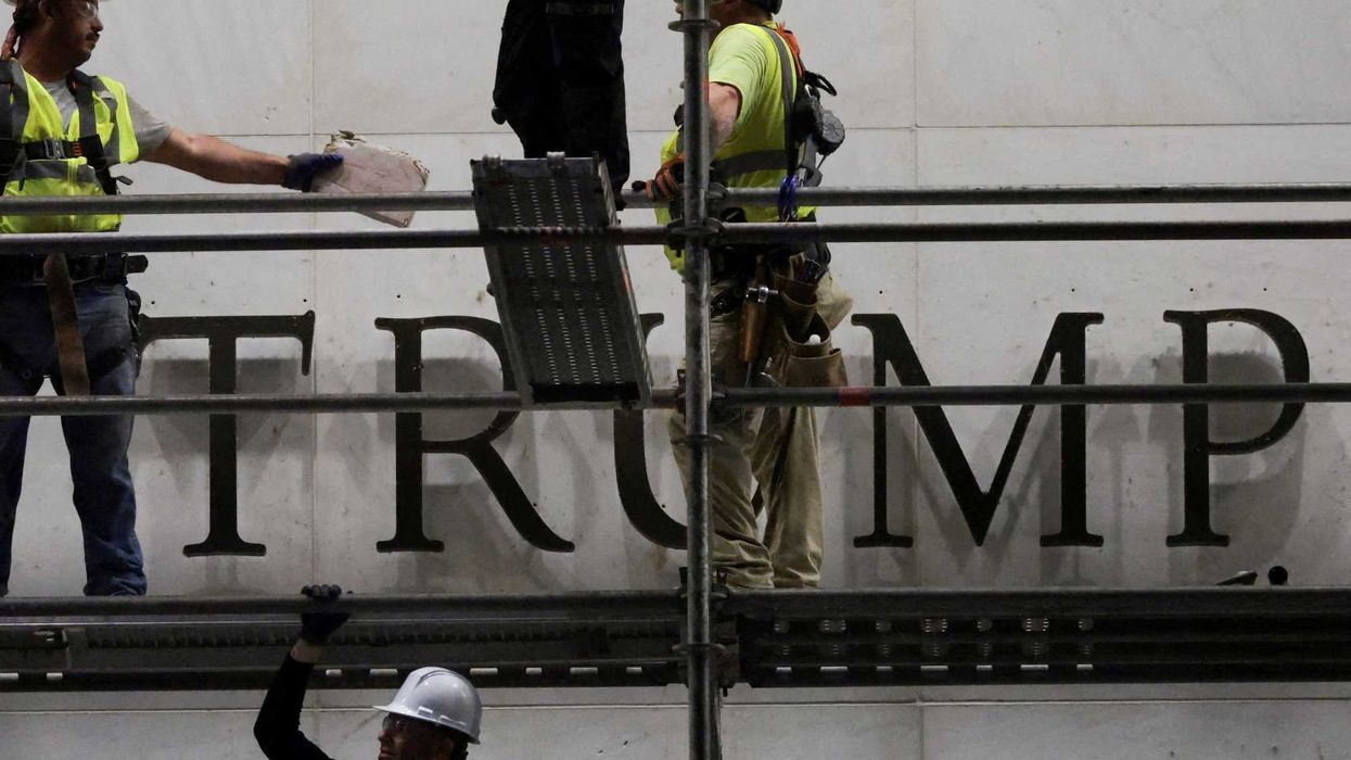 Workers prepare to remove lettering from the Kennedy Center after a judge ordered the removal of President Trump’s name. - alternet.org