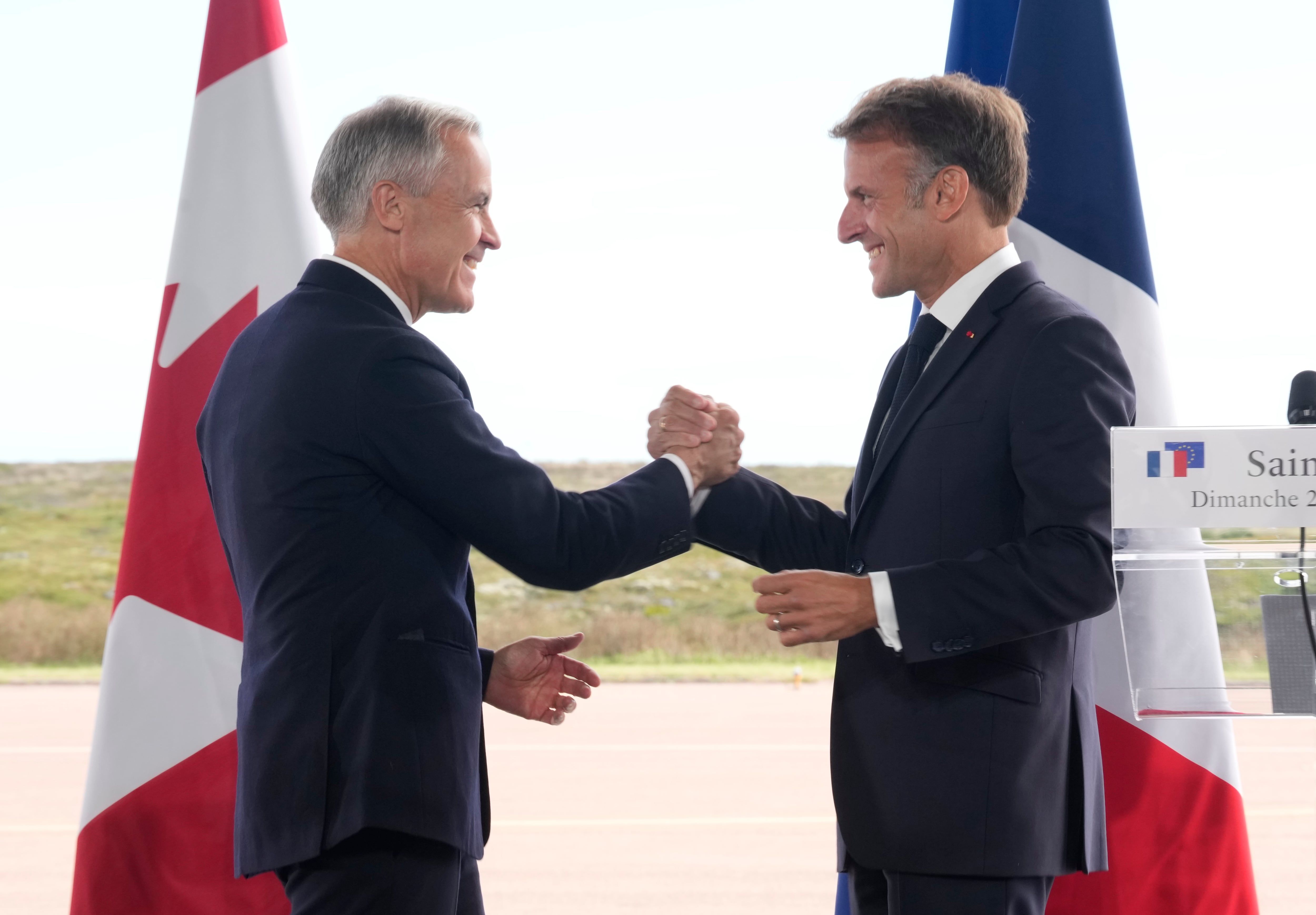 French President Emmanuel Macron and Prime Minister Mark Carney embrace after remarks in Saint-Pierre, Saint-Pierre-et-Miquelon. - The Canadian Press