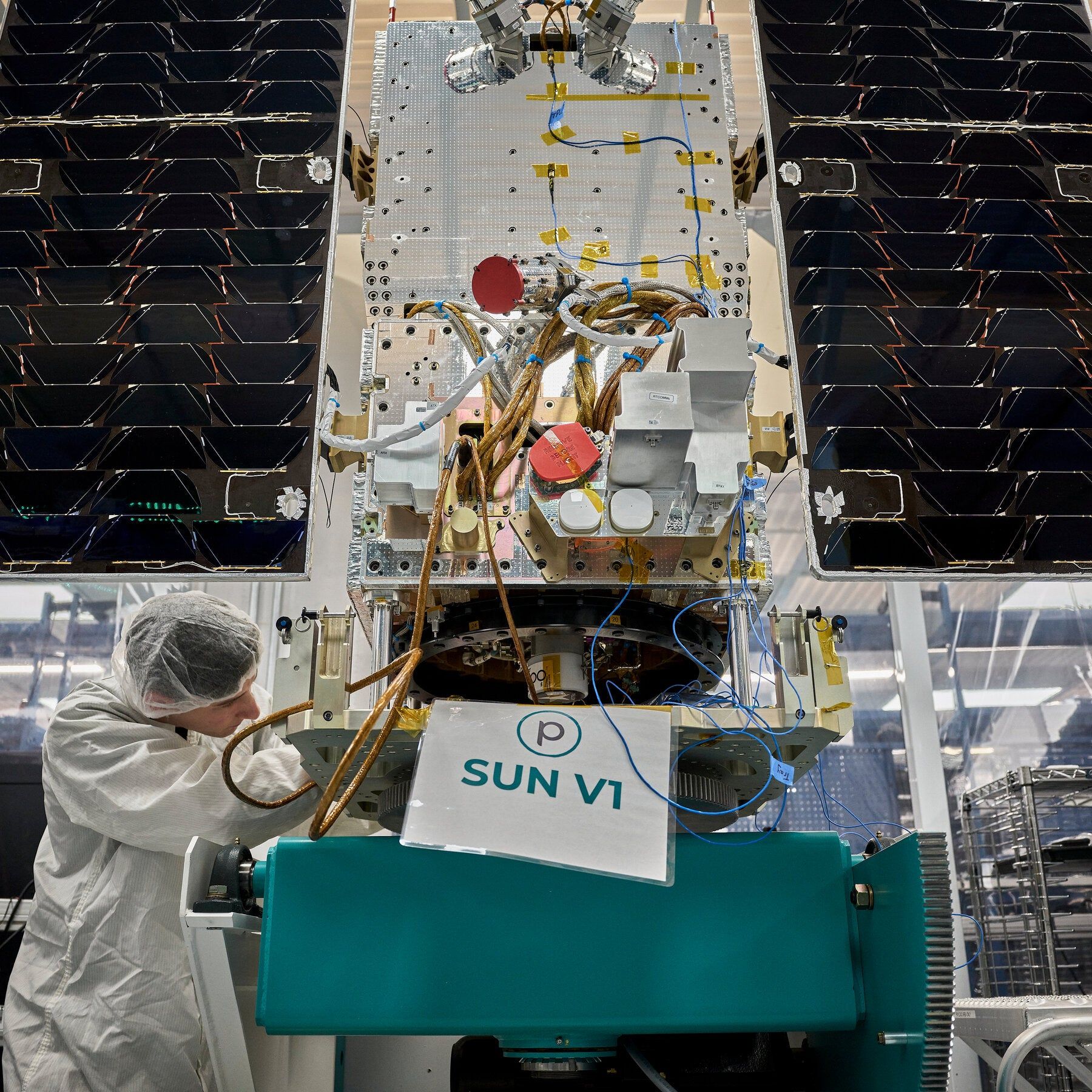 A Planet Labs technician inspects solar panels and wiring on a Google-commissioned satellite before a launch-vibration test. - The New York Times